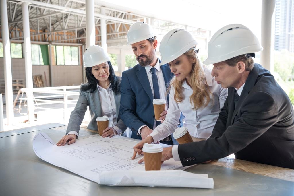 Group of contractors in formal wear working with blueprints